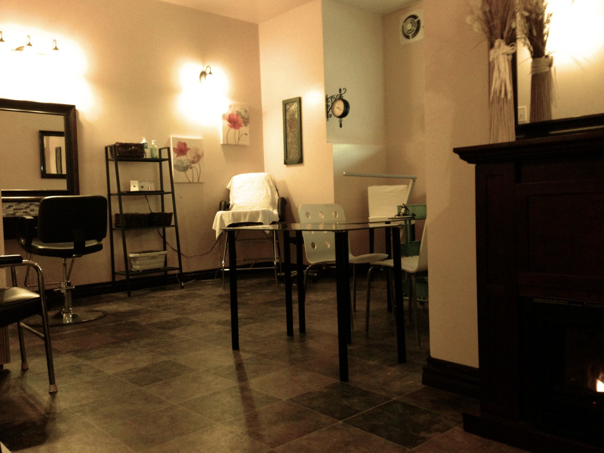 A room with a fireplace, a desk with a chair, a small table with chairs, and a mirror on the wall.