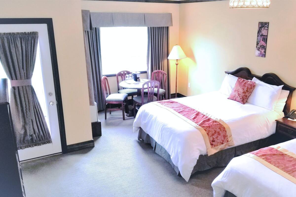 A hotel room with a bed, bedside tables, a desk, and chairs.
