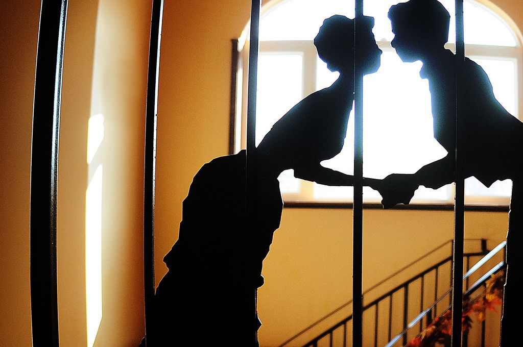 A silhouette of a couple embracing in a doorway with a staircase in the background.