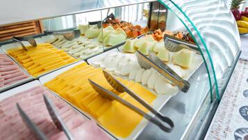 Buffet com diversos alimentos, incluindo queijos, frutas e carnes.