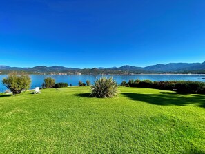 Una zona erbosa con vista libera su un lago e montagne sullo sfondo.