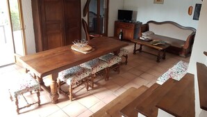 Un comedor con una mesa de madera, bancos y un televisor sobre un mueble de madera.