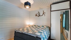Une pièce comprenant un lit, une armoire, un miroir et une décoration murale représentant des bois de cerf.
