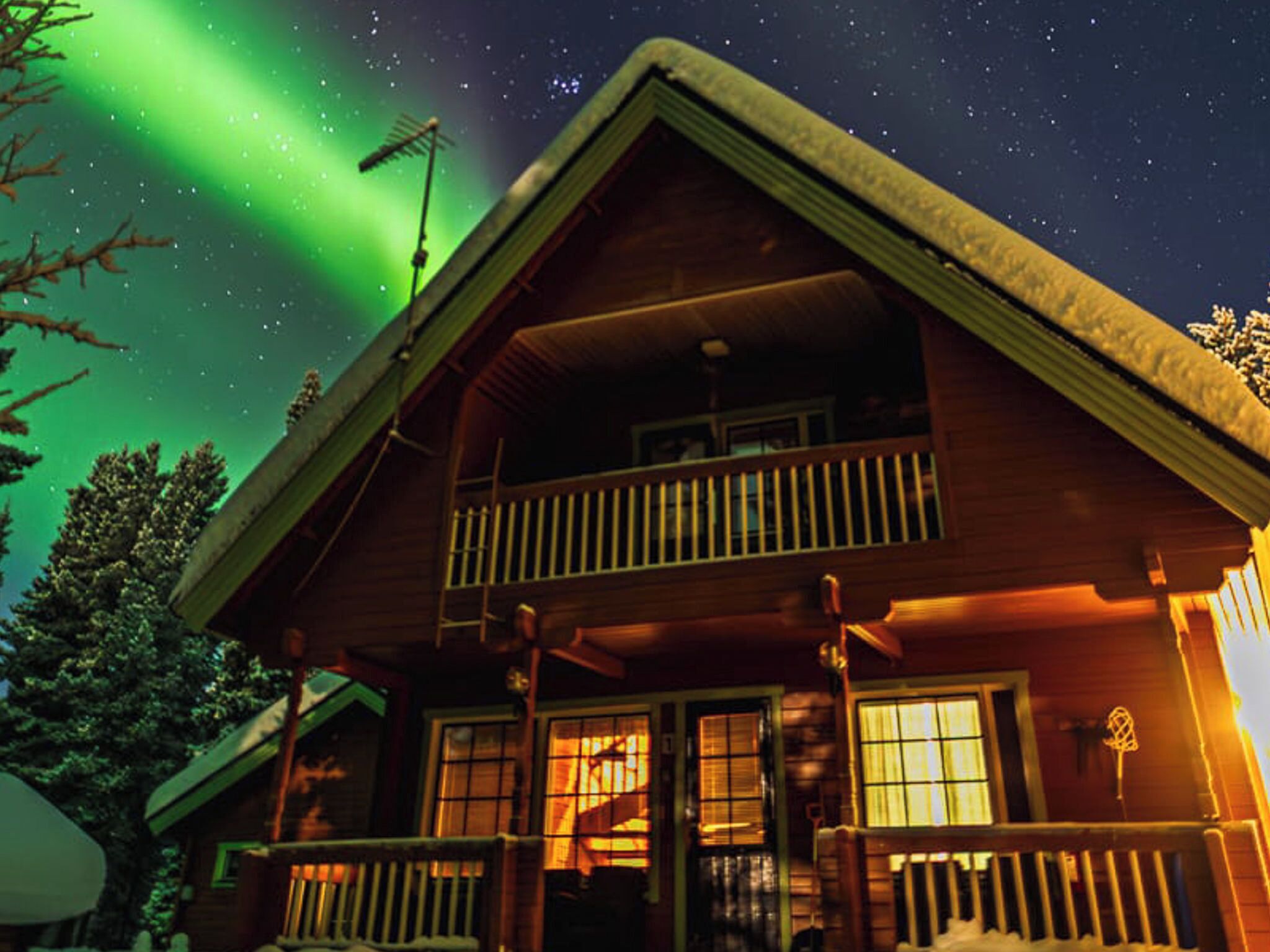 Une cabane en bois dotée d’un balcon, de fenêtres et d’un toit recouvert de neige.