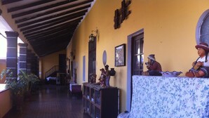 A corridor with a staircase, a sofa with a floral cover, and a display of figurines. - Hostal Tres Mascaras (Ayacucho)