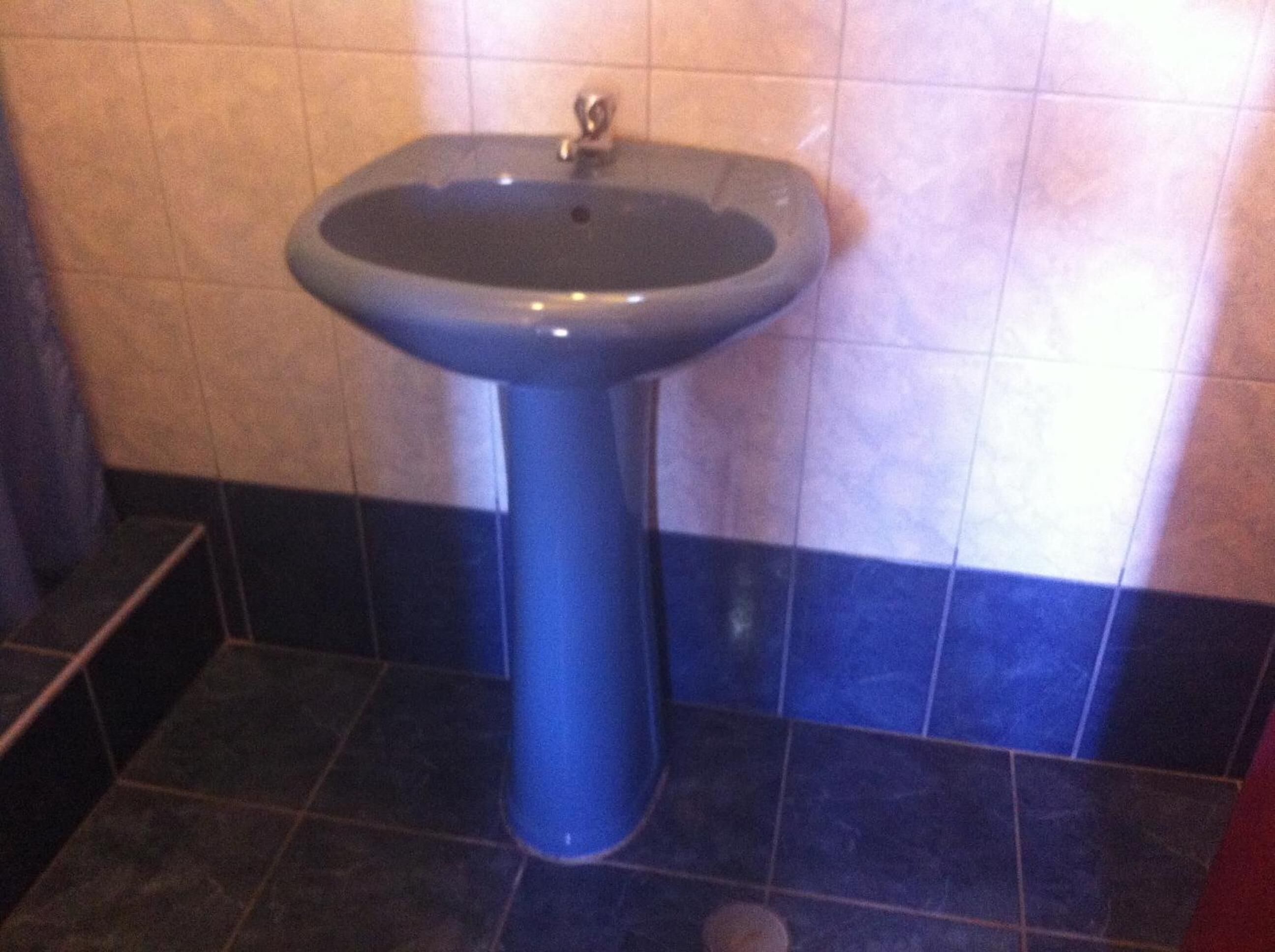 Un baño con lavamanos pedestal y paredes de azulejos.