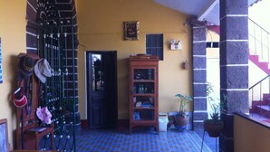 A room with a patterned floor, a wooden door, a bookshelf, and a staircase. - Hostal Tres Mascaras (Ayacucho)
