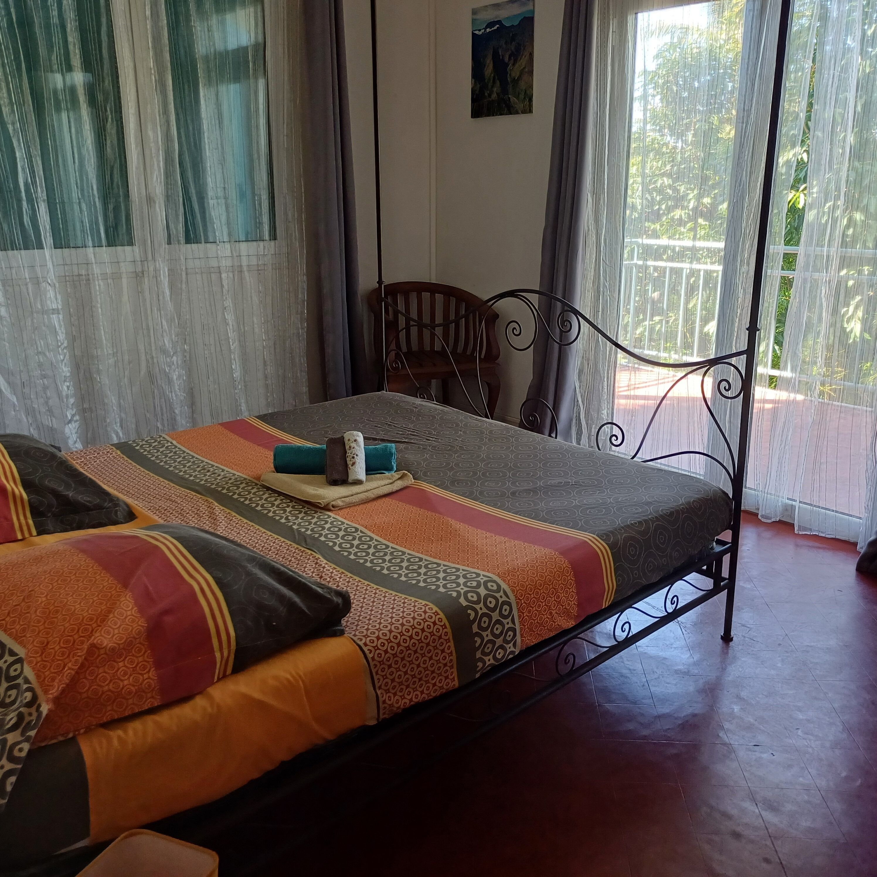 Un lit avec une literie à motifs, une petite table avec une serviette et une chaise.