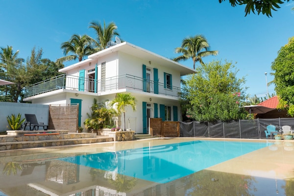 Villa vue de la piscine avec espace repas Ă l'ombre des manguiers Ă droite