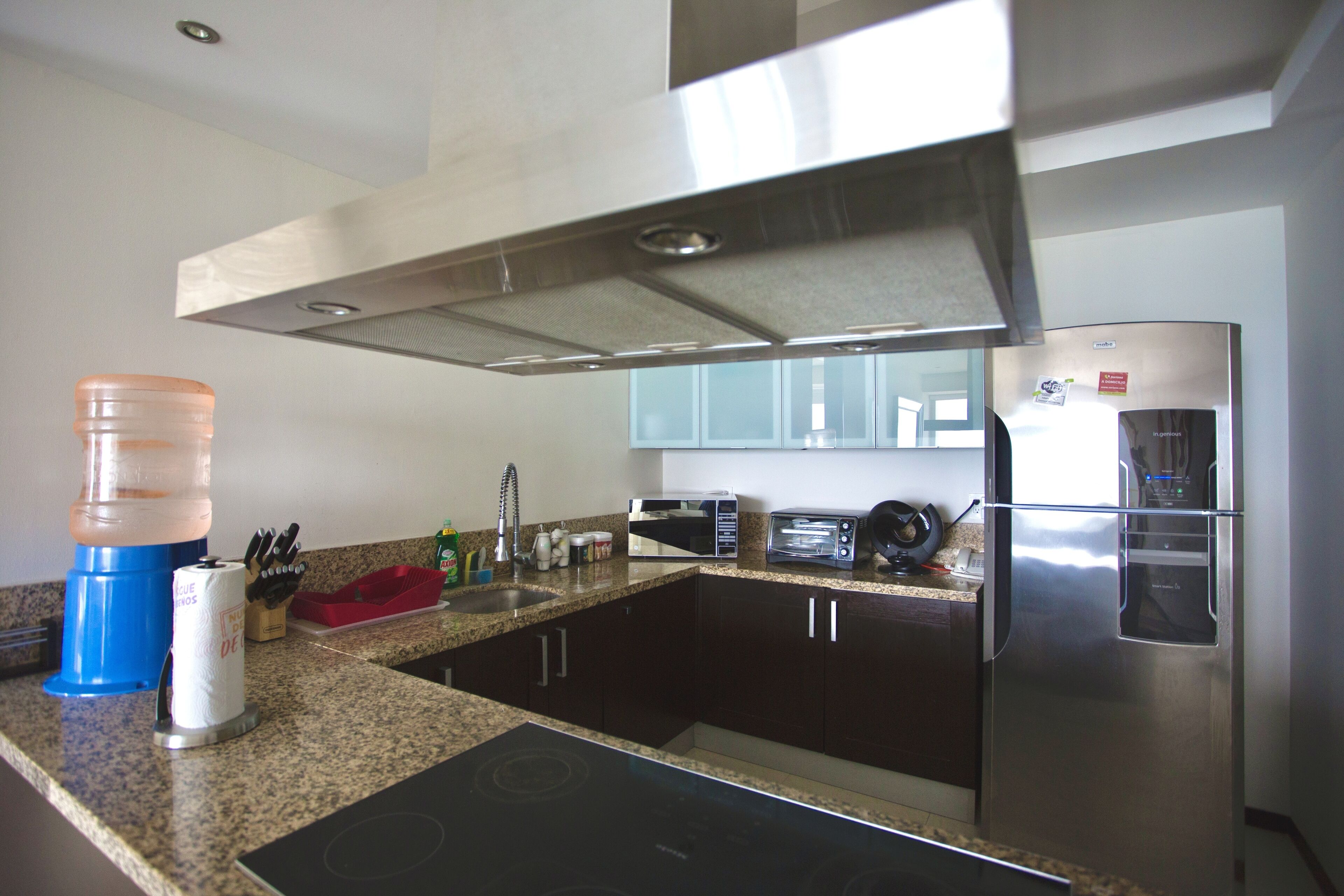 A modern kitchen with dark cabinets, a stainless steel refrigerator, a microwave, and a built-in oven.