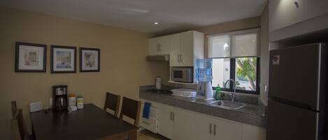 A compact kitchen with white cabinets, a stainless steel refrigerator, a coffee maker, and a water dispenser.
