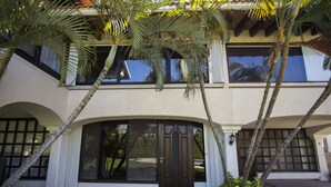 A two-story house with a large front door, arched windows, and a covered porch area.