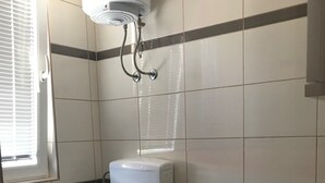 Une salle de bain équipée de toilettes, d’un bidet et d’un chauffe-eau fixé au mur.