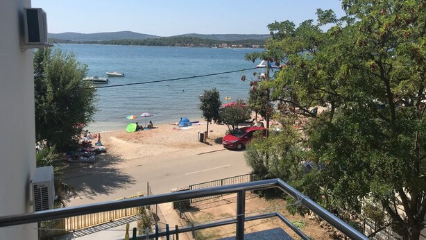 Une plage avec des tentes et des parasols, une route et une voiture.