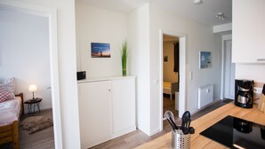 Een moderne keuken met witte kasten, een koffiezetapparaat en een plant op het aanrecht.