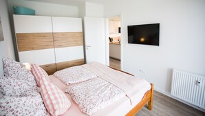 Een slaapkamer met een bed, een kledingkast, een televisie en een radiator.