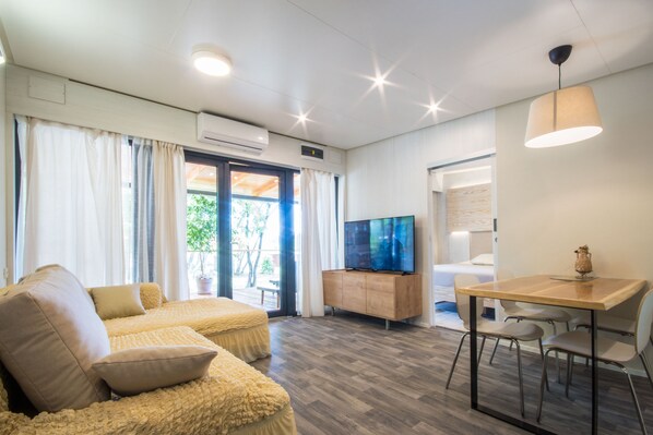 A modern living room with a sofa, TV, dining table, and chairs. - Unique, romantic and completely private (Labin)
