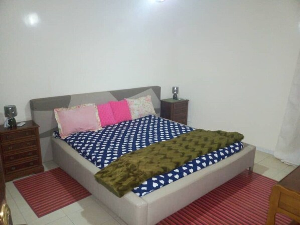 A bedroom with a bed, two nightstands, a chair, and a red striped rug.