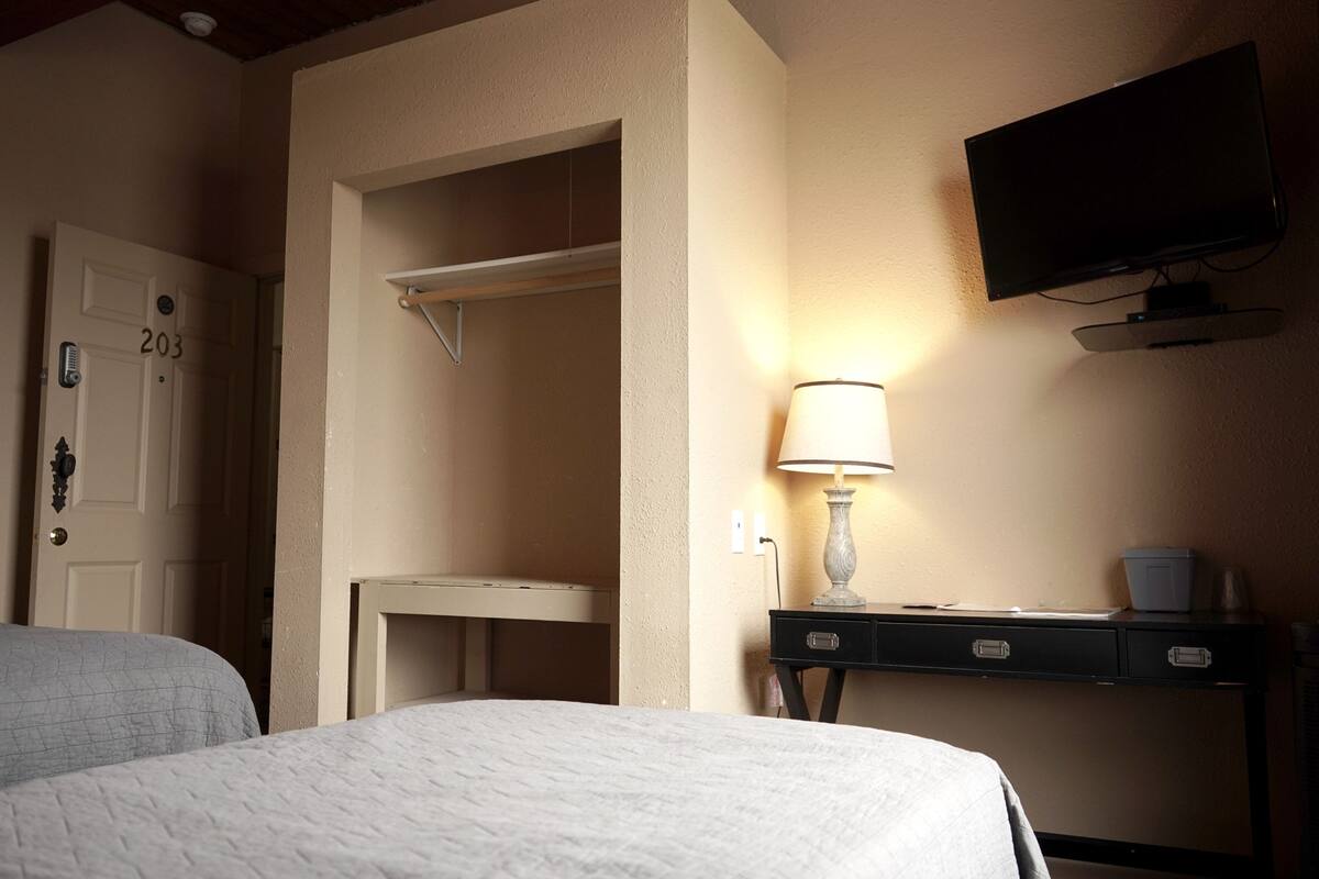 Une chambre d’hôtel comprenant un lit, un bureau avec une lampe, une télévision et une armoire.