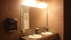 A bathroom with two sinks, a mirror, and a soap dispenser.