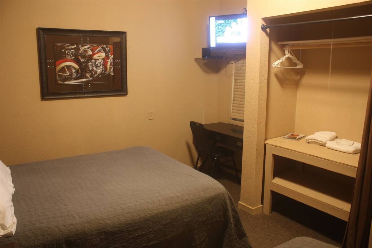Une chambre d’hôtel équipée d’un lit, d’un bureau, d’une chaise, d’une télévision et d’une armoire.
