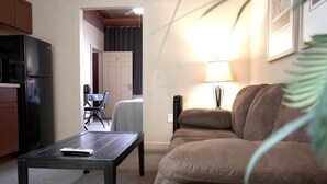 Un salon comprenant un canapé, une table basse, une lampe et un réfrigérateur.