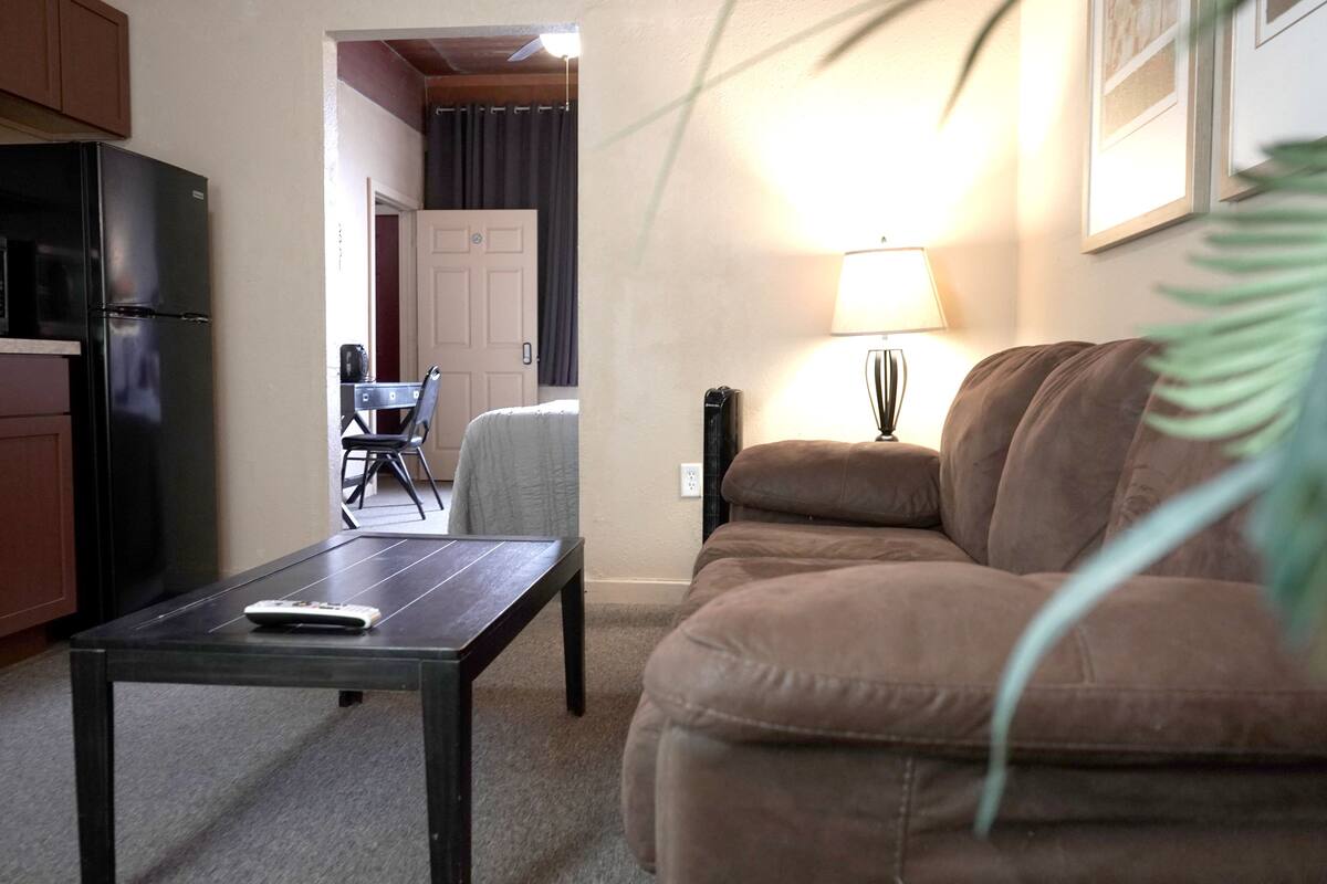 Un salon comprenant un canapé, une table basse, une lampe et un réfrigérateur.
