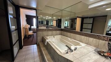 A modern bathroom with a large bathtub, a mirror, and a chair.