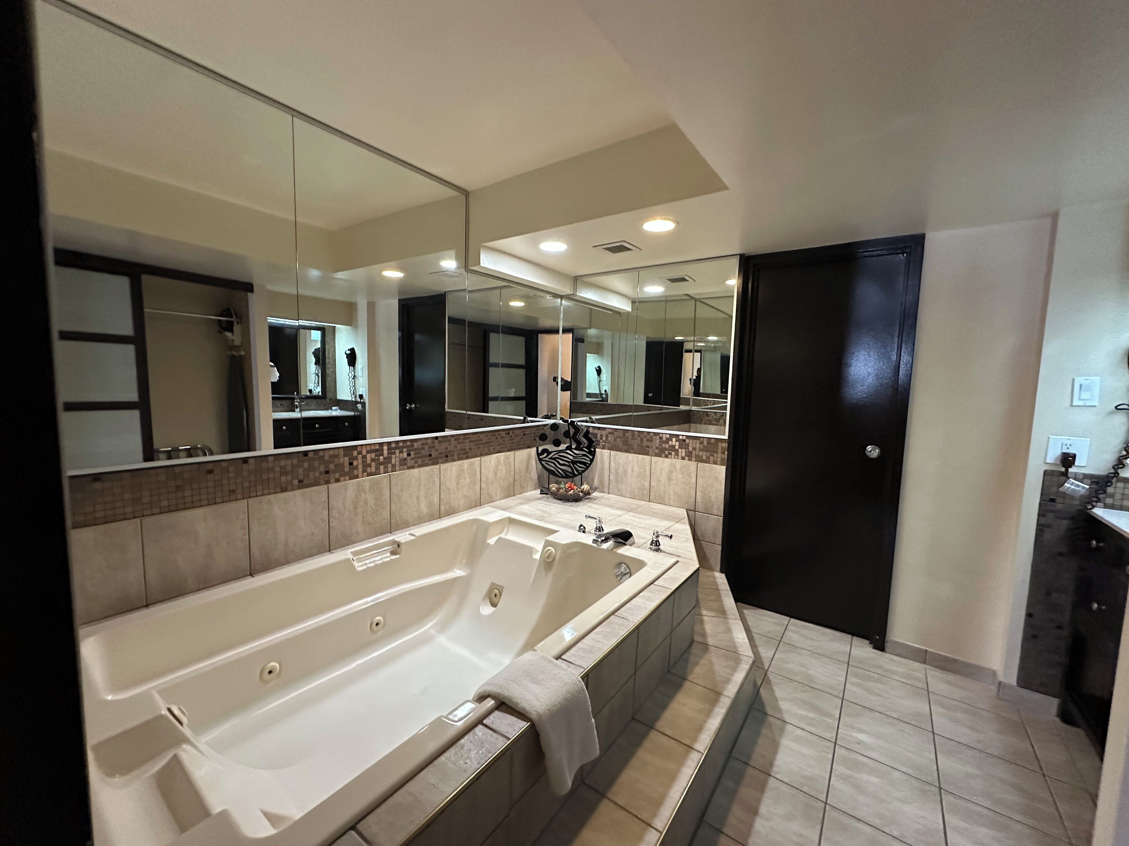 Une salle de bain moderne avec une grande baignoire, un miroir et un sol carrelé.