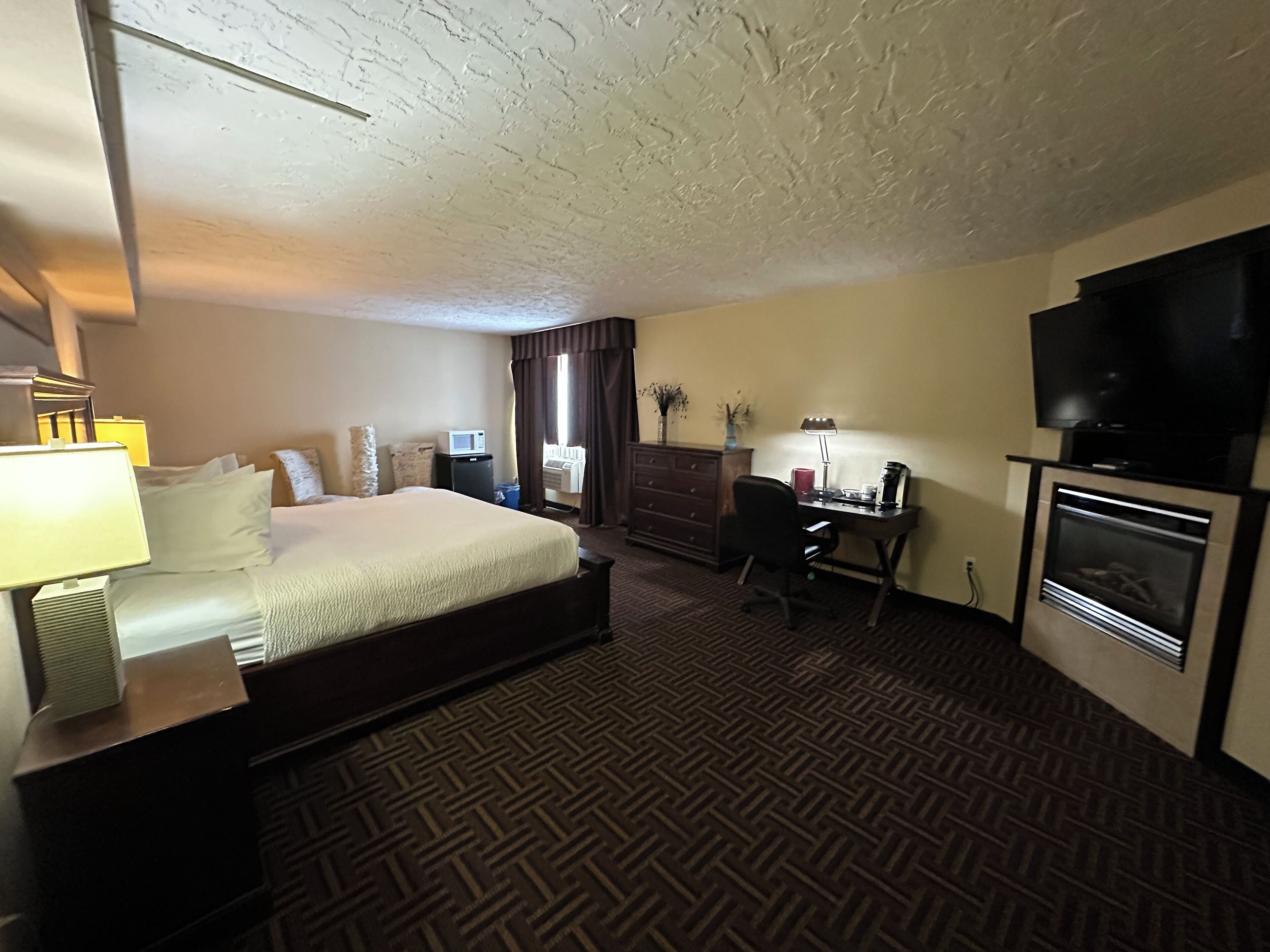 Une chambre d’hôtel équipée d’un lit, d’un bureau, d’une télévision et d’une cheminée.