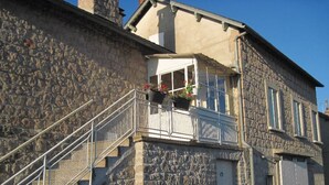 Un bâtiment en pierre doté d’un balcon, d’un escalier et d’une porte.