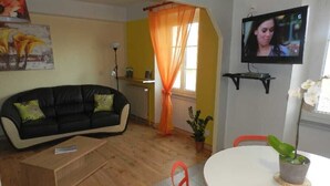 Un salon avec un canapé noir, une table blanche et un téléviseur.