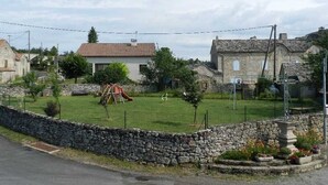 Un village rural avec des maisons en pierre, un terrain de jeux recouvert d’herbe et un mur en pierre.