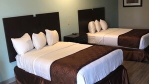 Habitación de hotel con dos camas, cada una con cabecera, mesita de noche y un cuadro en la pared.