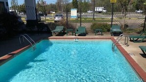 Piscina rectangular con un indicador de profundidad de 3 pies, rodeada por un borde de ladrillo y sillas de descanso verdes.