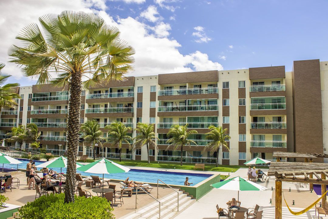 Et hotel med flere balkoner, swimmingpool og udendørs siddeområder.
