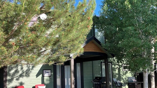Een lodge met een overdekte veranda, buitenzitplaatsen en een bordje dat aangeeft dat het een camping is.