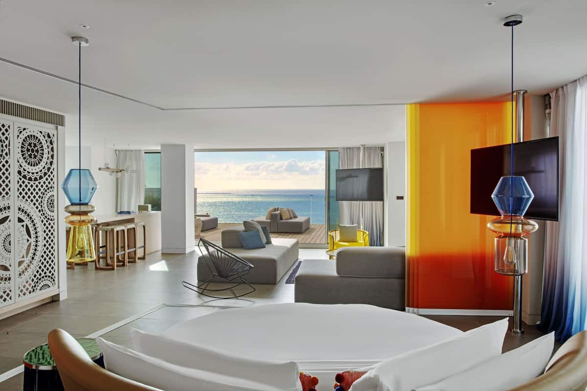 Habitación de hotel moderna con una cama grande, televisión y vistas al océano.