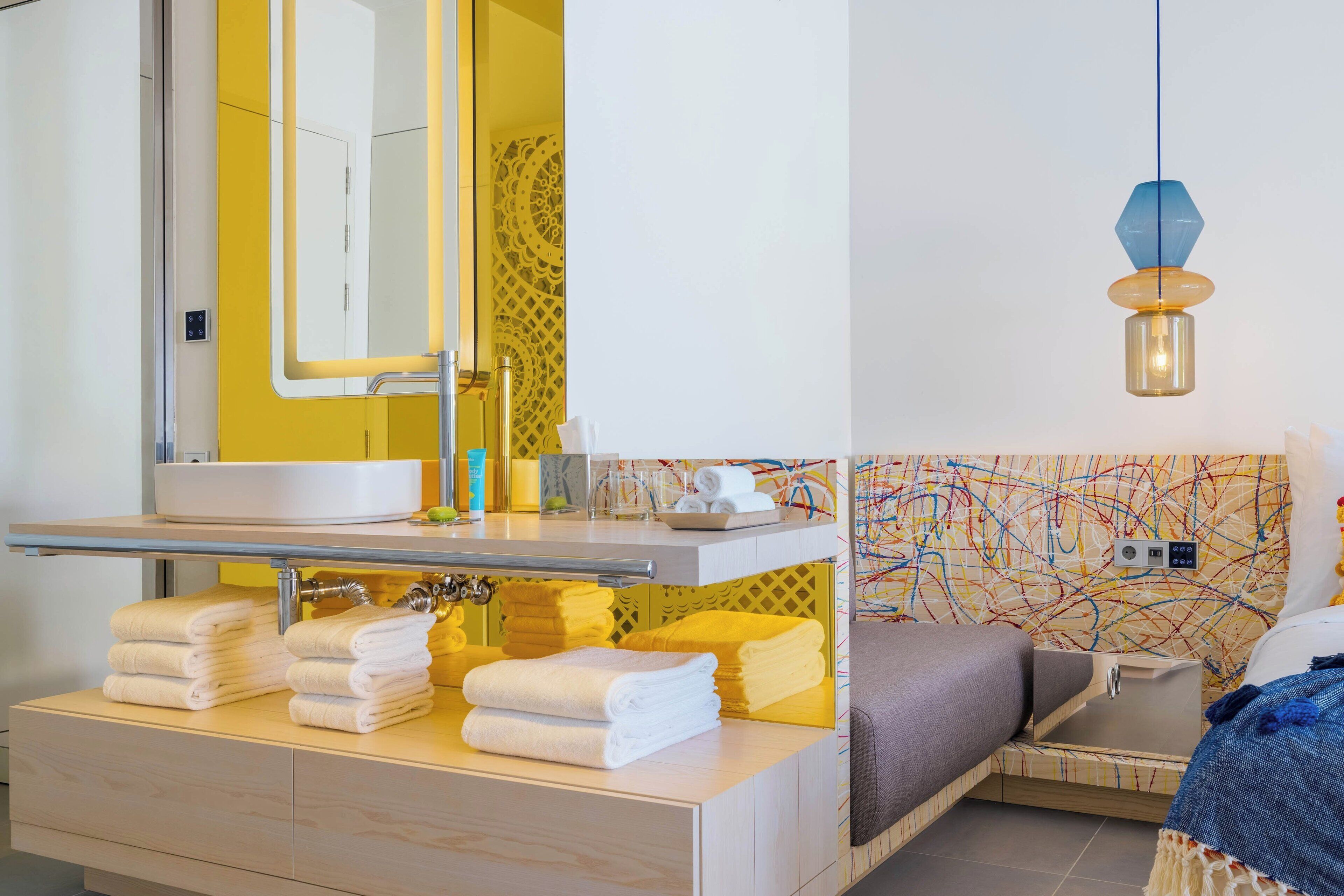 A modern bathroom with a large mirror, a sink, and neatly folded towels.