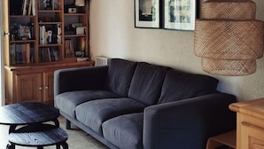 A cozy living room with a dark grey sofa, a wooden bookshelf filled with books, a small round table, and a woven light fixture. - House of subdivision, Le Croisic  (Le Croisic)