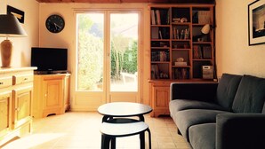 A cozy living room with a wooden ceiling, a television on a wooden cabinet, a bookshelf, a grey sofa, and a small round table. - House of subdivision, Le Croisic  (Le Croisic)