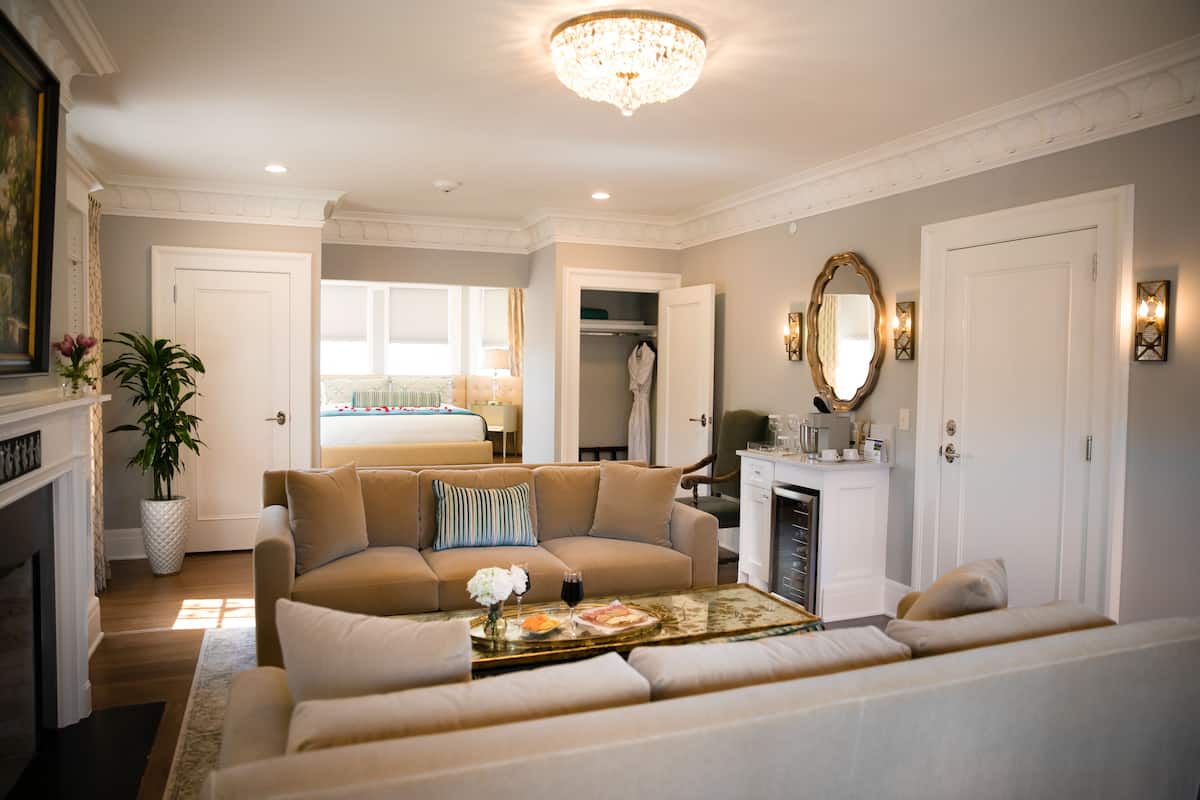 A well-lit living room with a beige sofa, a coffee table with a tray, and a chandelier.