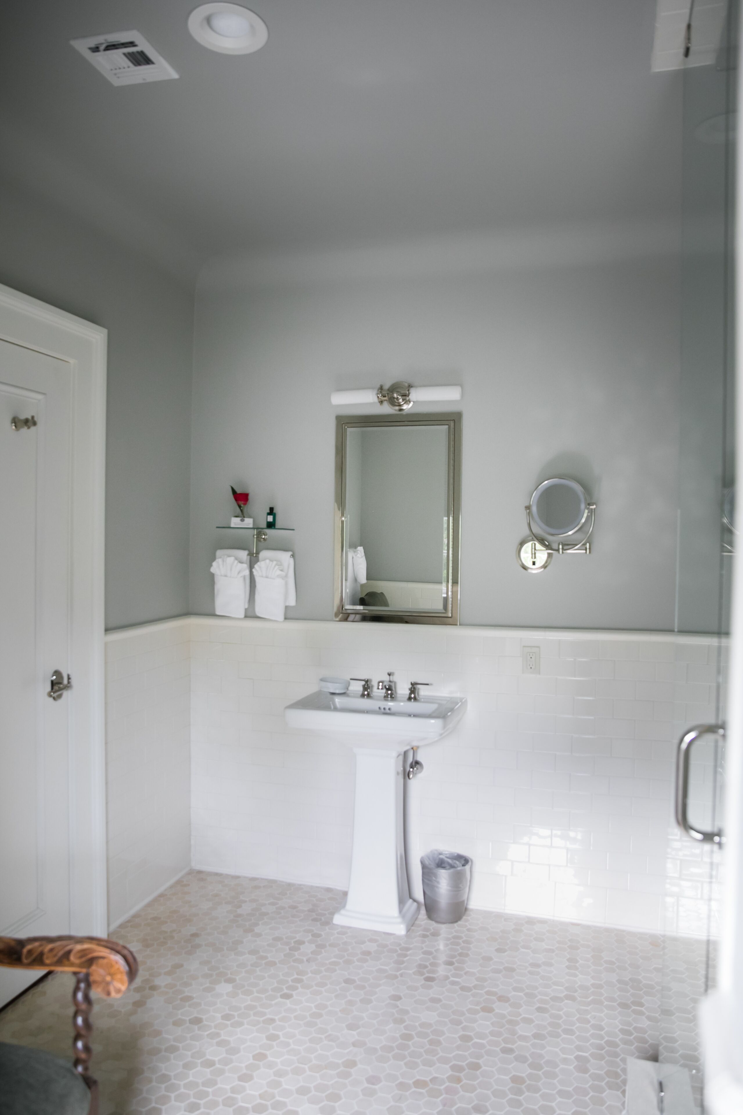 Un baño con lavamanos blanco, espejo y toallero.