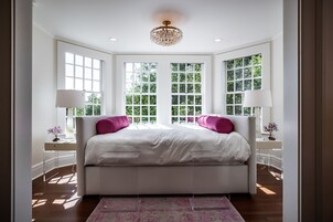 Un dormitorio espacioso con una cama grande, dos ventanas y un candelabro.