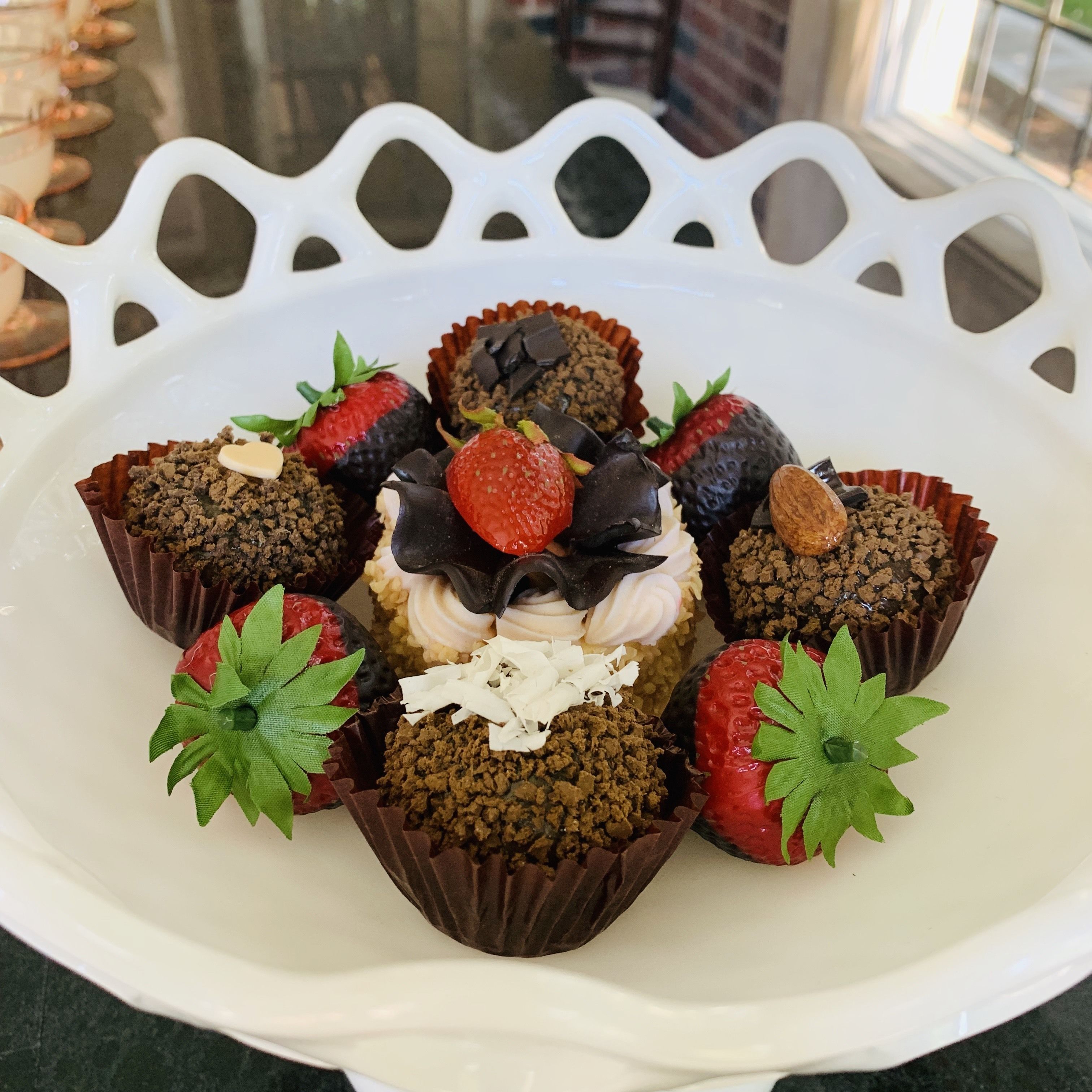 Un plato decorativo blanco con cupcakes de chocolate y fresas.