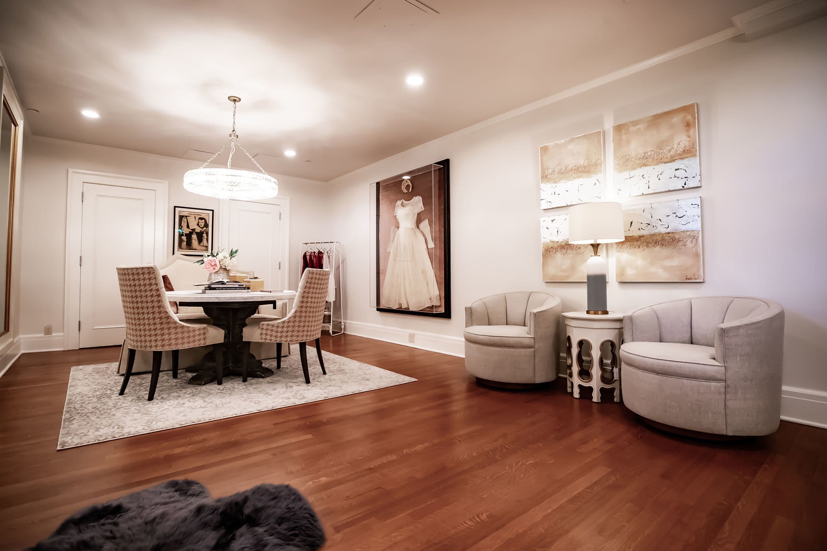 A dining area with a chandelier, a dining table with chairs, and a large framed artwork on the wall.