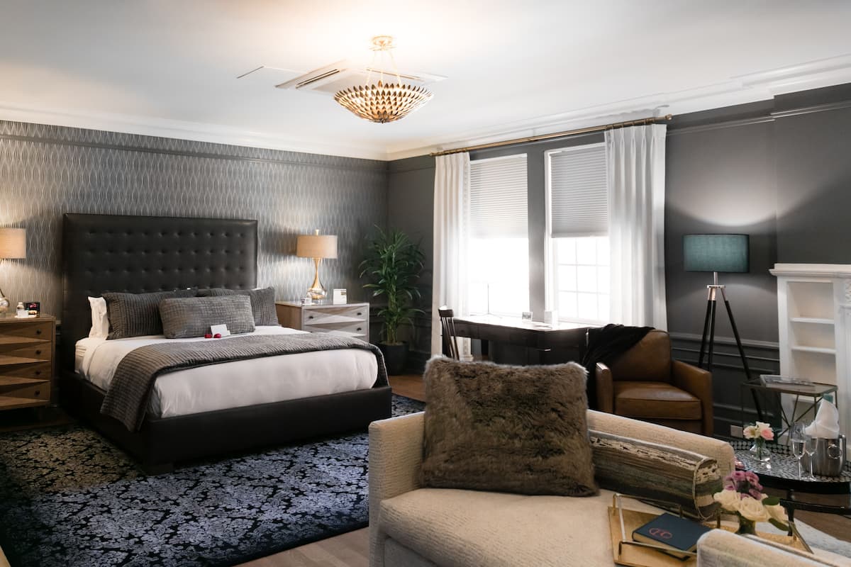 A modern bedroom with a large bed, a desk, a sofa, and a television.
