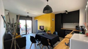 Eine moderne Küche mit Essbereich, einem schwarzen Sofa und einem großen Fenster.