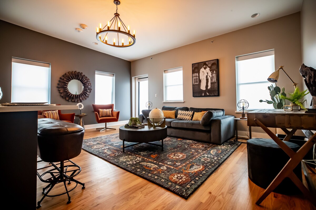 A modern living room with a dark leather sofa, a round coffee table, and a patterned rug.