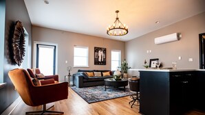 A modern living room with a sofa, a coffee table, and a dining area with a kitchen island. - Duets Bed & Breakfast (Tulsa)